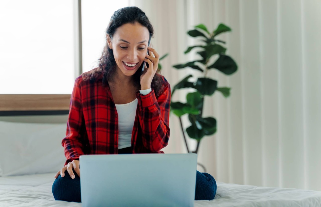 Mujer sentada frente a una computadora que habla por teléfono.