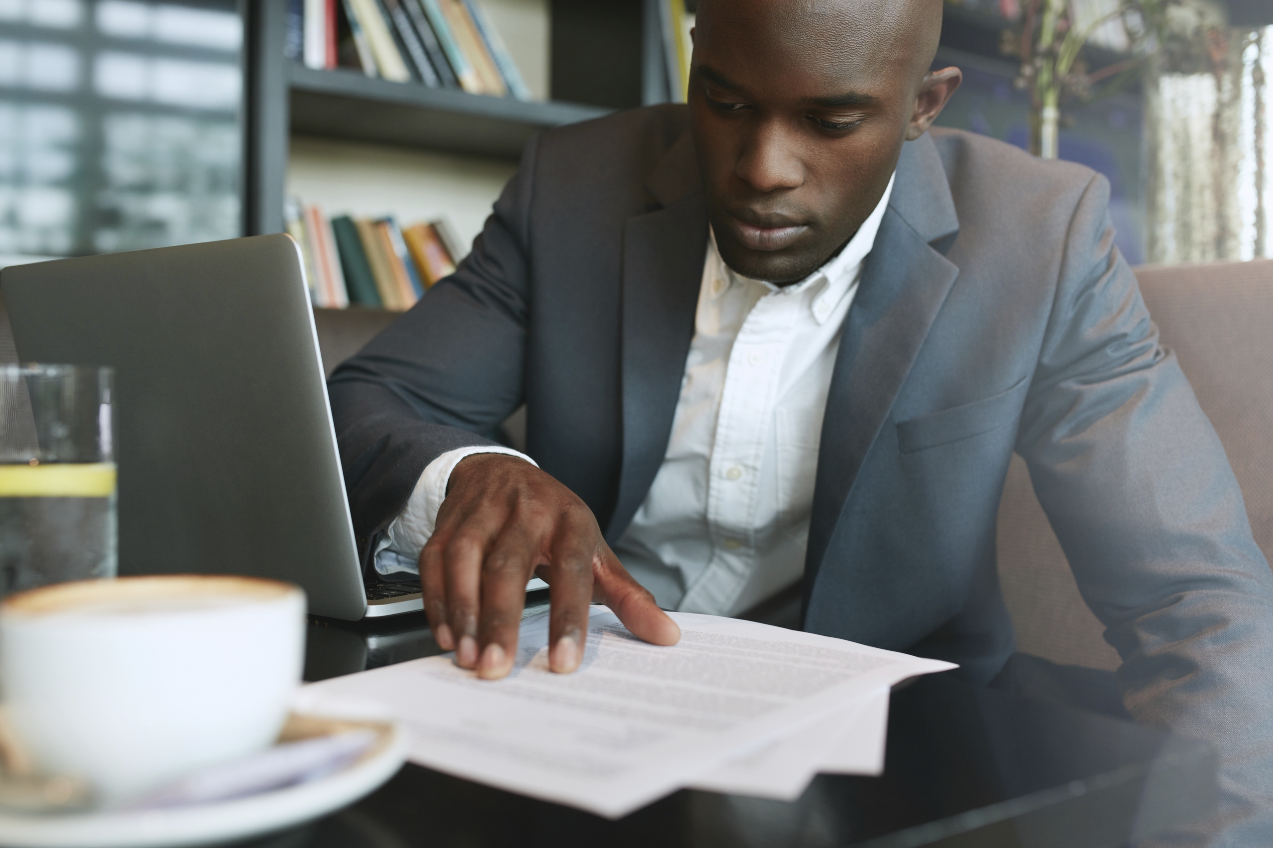 Businessman sitting at a computer looking at papers