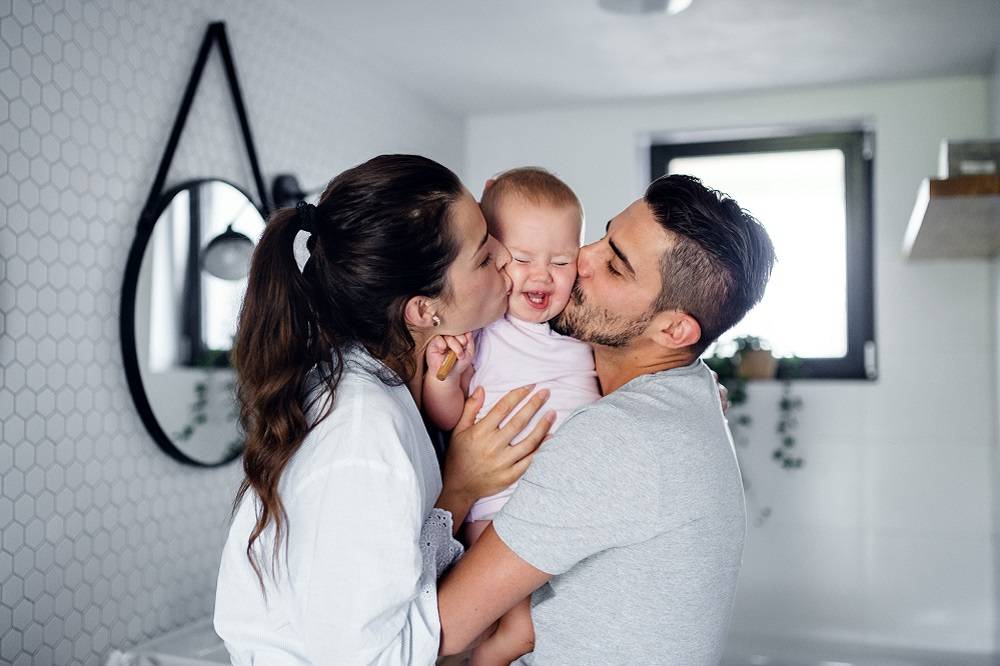 Mom and dad kiss a smiling baby on the cheeks. With BCBSIL, navigate the Special Enrollment Period to enroll.