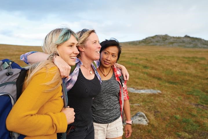 Three women smiling while on a hike