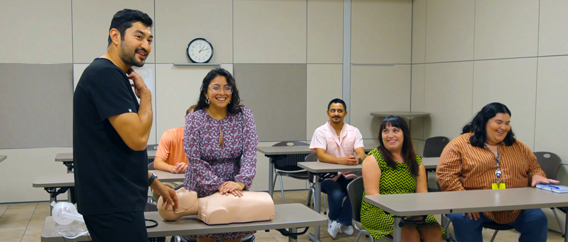 Instructor teaches woman to perform CPR on dummy