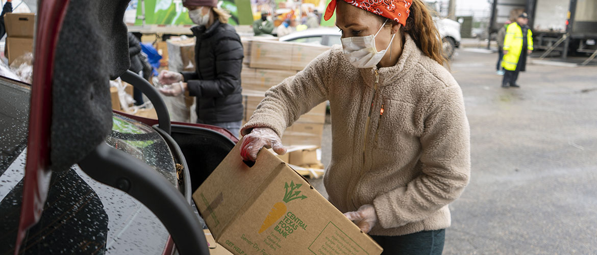 Food bank volunteer loads boxes into cars at drive-thru event