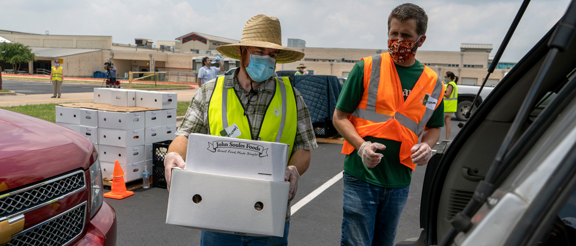 A food bank worker loads boxes into cars at drive-thru event