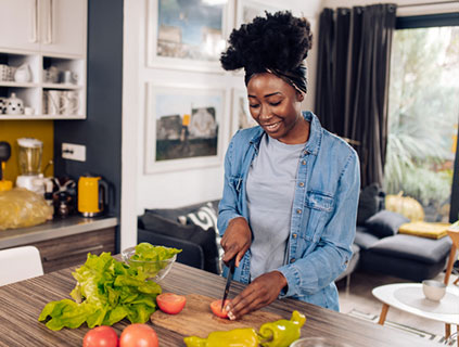 Young woman in her kitchen slicing healthy vegetables