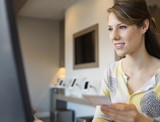 Woman seated at a computer with an ID card in her hand.