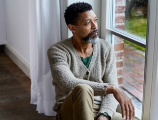 Middle-aged man sitting in a window and looking outside.