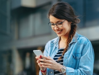 Young woman reading a message on the phone in the city 