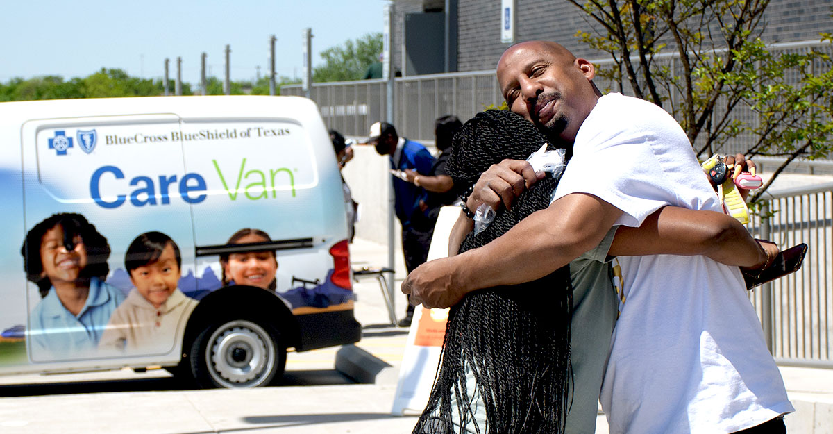 Dos amigos abrazándose en frente a Care Van®