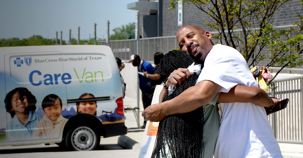 Two friends warmly embrace in front of Care Van®