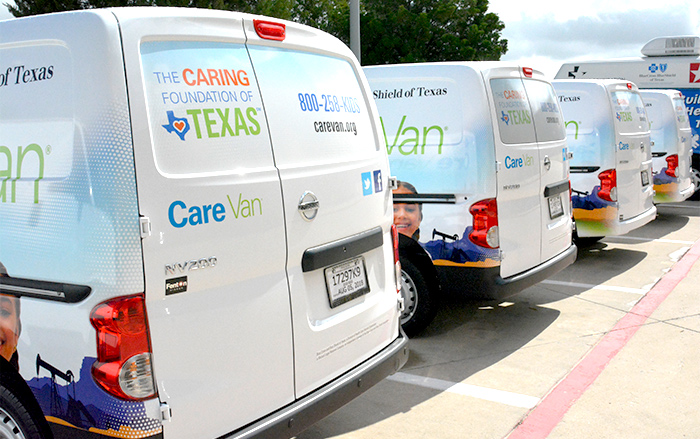 Una fila de Care Vans con el logotipo de Caring Foundation of Texas.