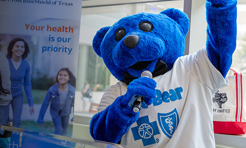 BCBSTX mascot Blue Bear with a microphone at an event.