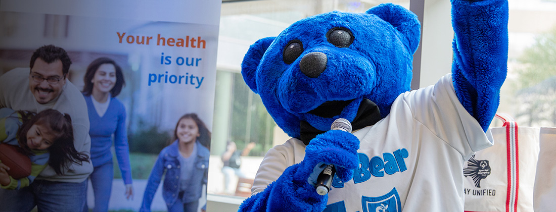 La mascota Blue Bear de BCBSTX con un micrófono en un evento.