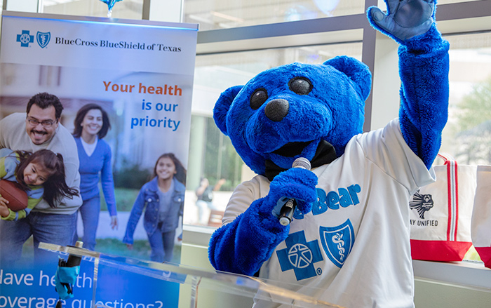 La mascota Blue Bear de BCBSTX con un micrófono en un evento.