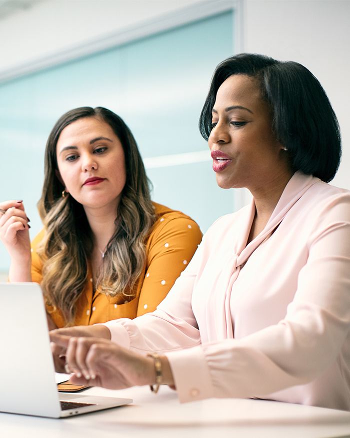 Two well-dressed women discuss business in an office. 