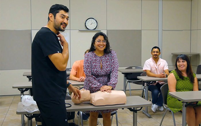 Medical instructor teaching a woman how to respond to a choking victim