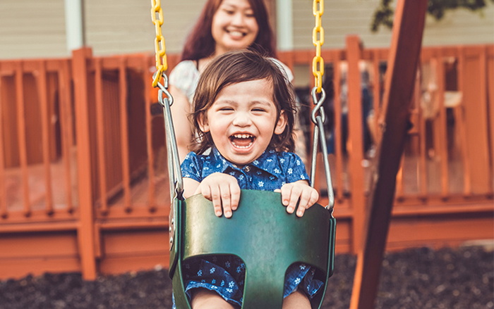 Child on swing getting pushed by mother