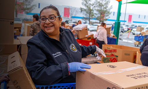 Una mujer clasifica cajas de comida en un evento de voluntariado