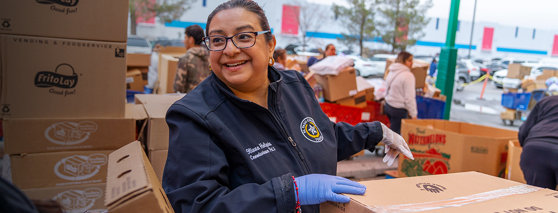 A woman sorts food boxes at a volunteer event