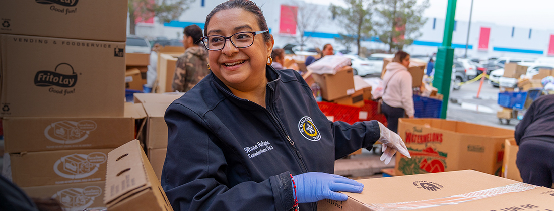 Una mujer clasifica cajas de comida en un evento de voluntariado