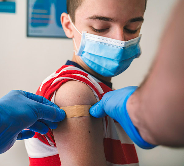 boy wearing mask gets routine childhood immunization