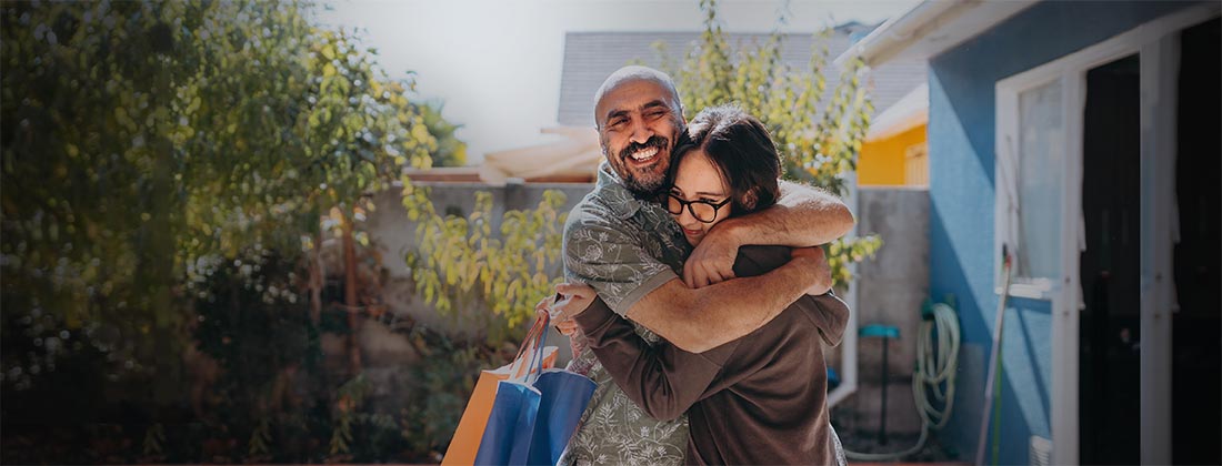 Man and daughter hugging outside on a sunny day