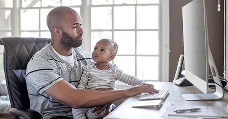 Imagen de un hombre con un bebé frente a una computadora