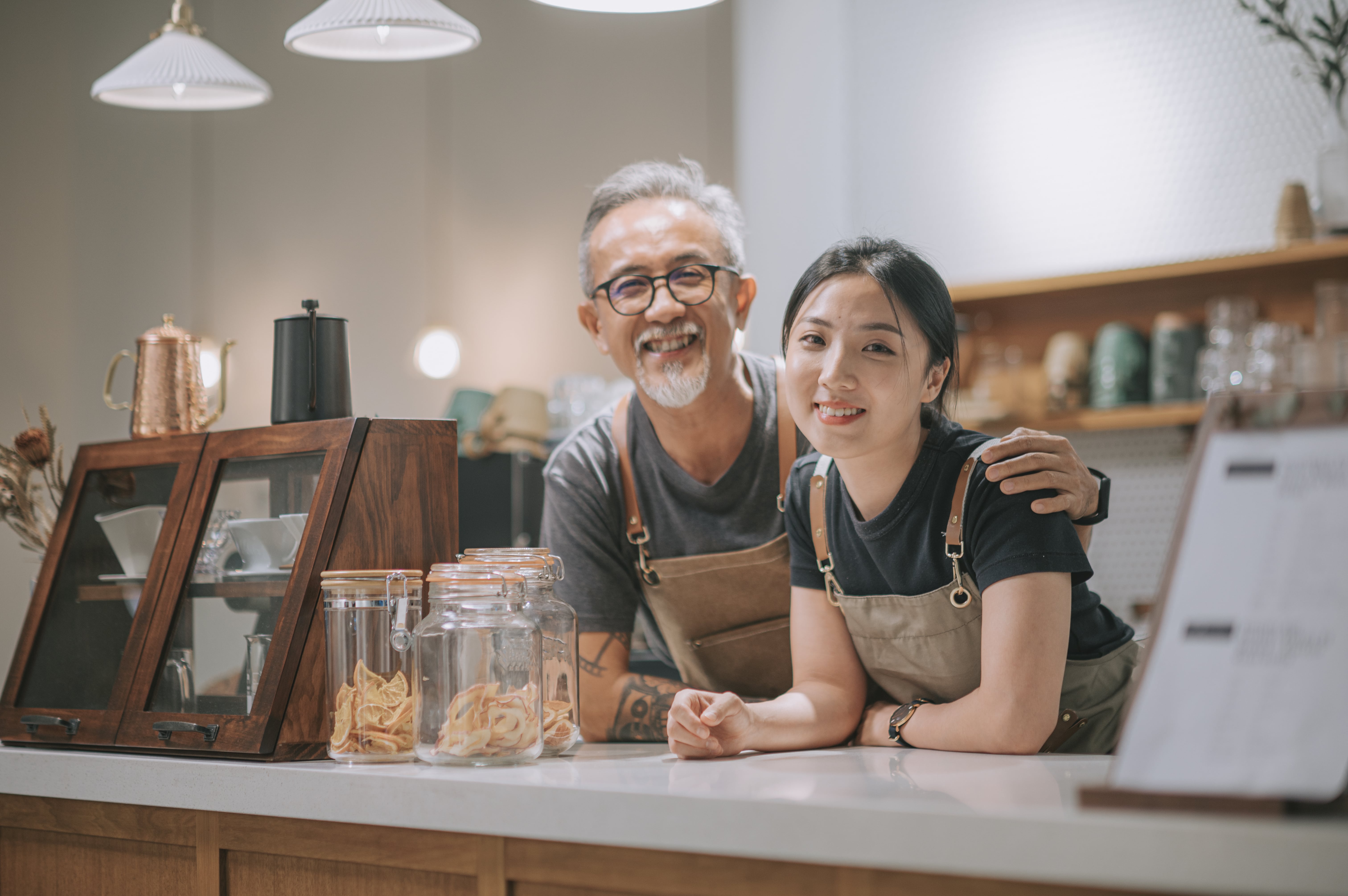  Man and woman wearing aprons standing behind a coffee counter